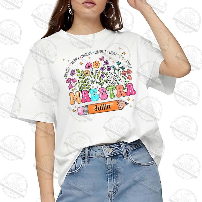 May include: White t-shirt with a colorful graphic of the word "Maestra" with a pencil and flowers. The text "Jullia" is written on the pencil.