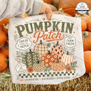 May include: A white t-shirt featuring a graphic design with the text PUMPKIN Patch, Fresh From The Patch, and Farm Fresh. The illustration includes six pumpkins with various patterns like plaid, leopard print, and flowers, plus foliage accents.