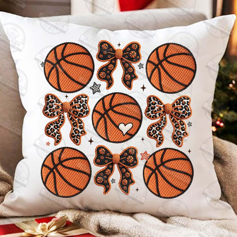 May include: White decorative pillow featuring a pattern of orange basketballs, leopard print bows, and basketball-themed bows. The basketballs have black lines and a heart design. Small star and plus symbols are also included.