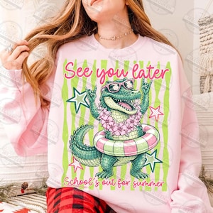 May include: Pink sweatshirt with a graphic of a cartoon alligator wearing sunglasses and a floral lei, inside a pink and green striped design. Text reads "See you later" and "School's out for summer".