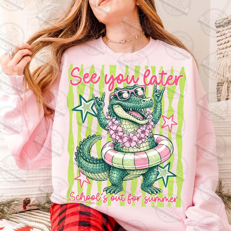 May include: Pink sweatshirt with a graphic of a cartoon alligator wearing sunglasses and a floral lei, inside a pink and green striped design. Text reads "See you later" and "School's out for summer".