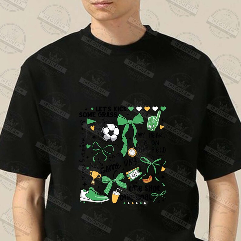 May include: Black t-shirt with a green, white, and gold graphic design featuring a soccer ball, bows, and the text "Let's Kick Some Grass", "My Heart Is On That Field", "Game Day", and "One Shot One Goal".