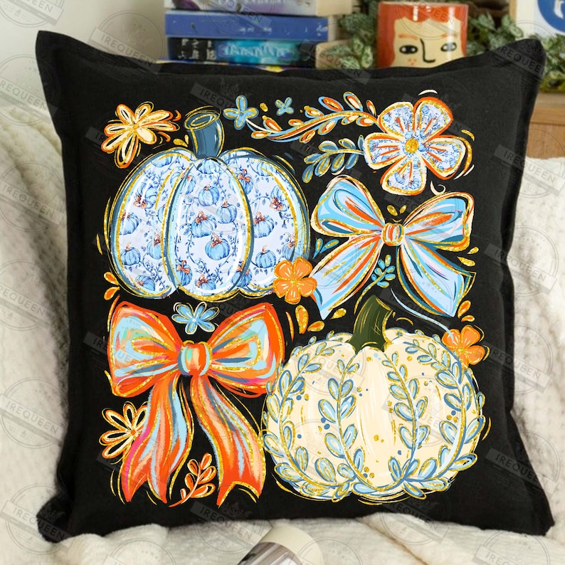 May include: Black square throw pillow featuring a colorful autumn design. The design includes two pumpkins, two bows, and floral accents in shades of blue, orange, and yellow. The pumpkins have intricate patterns, and the bows have a gradient effect.