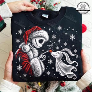 Puede incluir: Una sudadera negra de cuello redondo con un gráfico de un esqueleto vestido con abrigo y gorro de Papá Noel rojo y blanco, tocando la nariz de un perro fantasma blanco. El diseño incluye copos de nieve blancos y el texto Boop en blanco.