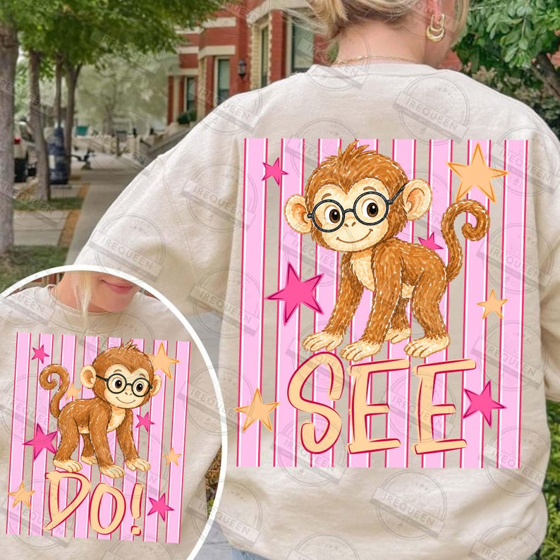 Puede incluir: Sudadera beige con un mono de dibujos animados con gafas, rodeado de estrellas rosas y rayas verticales. La palabra "SEE" est&aacute; impresa debajo. El dise&ntilde;o se repite a menor escala.