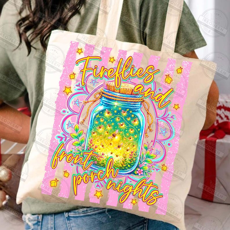 May include: A beige tote bag with a colorful design. The design features a blue jar filled with fireflies, surrounded by flowers and stars, with the words "Fireflies and front porch nights" in yellow and pink. The bag has a striped pink background.
