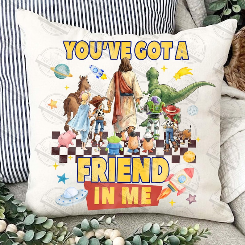 May include: A white decorative pillow featuring a colorful graphic with the text "YOU'VE GOT A FRIEND IN ME". The design includes cartoon characters and a depiction of Jesus. The pillow has a checkered pattern at the bottom.