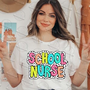 May include: A white t-shirt with the words "SCHOOL NURSE" in colorful, polka-dotted letters.