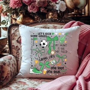 May include: White throw pillow with a green, black, and white soccer-themed design. The pillow features the text "Let's Kick Some Grass", "My Heart Is On That Field", "Game Day", and "One Shot One Goal".
