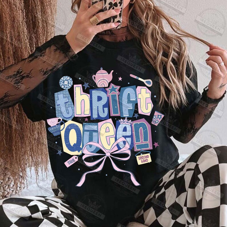 May include: Black crew neck t-shirt with the text "Thrift Queen" in a colorful, whimsical design. The graphic includes a pink bow, stars, and small illustrations of tea cups and a teapot. The shirt also has a "Second Hand" tag.