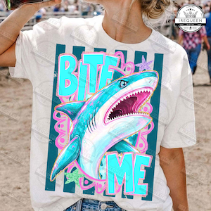 May include: White t-shirt with a turquoise shark design and the words "BITE ME". The shark has a pink mouth, and the design includes teal stripes and pink accents. A casual graphic tee.