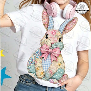 Peut inclure: T-shirt blanc avec un motif de lapin patchwork. Le lapin est composé de tissus floraux, à carreaux et à pois, avec un nœud rose. La personne portant le t-shirt a un casque rose autour du cou. Le design est de style mignon et fantaisiste.