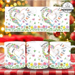 Può includere: Tazza in ceramica bianca con un design a cuore floreale, le parole "Nonna" e "Mamma", farfalle e nomi. Un bordo floreale colorato è in basso. È un articolo da regalo.