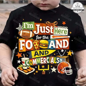 Op de afbeelding: Zwart t-shirt met een kleurrijke afbeelding met de tekst "I'm Just Here for the Food and Commercials". Het ontwerp bevat een voetbal, pizza, burger, snacks, een drankje, een voetbalhelm en een tv.