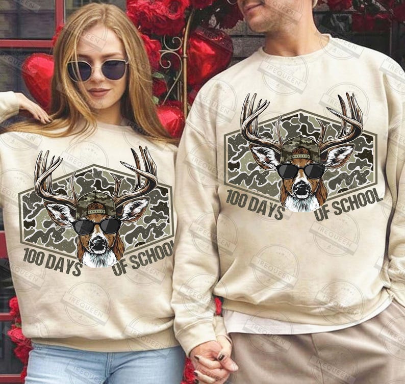 Puede incluir: Sudaderas beige con un gr&aacute;fico de ciervo con gafas de sol y un sombrero de camuflaje. El gr&aacute;fico est&aacute; dentro de un hex&aacute;gono con el texto "100 DAYS OF SCHOOL". Llevadas por un hombre y una mujer.