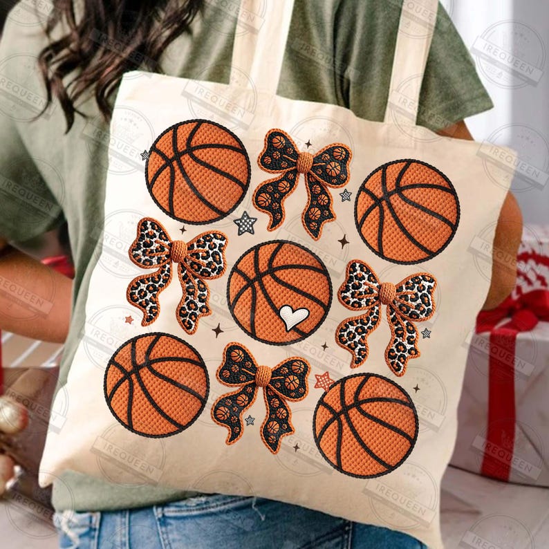 May include: A cream-colored tote bag featuring embroidered basketballs and bows. The basketballs are orange with black lines, and the bows have leopard print and black patterns. Small star and heart details are also included.