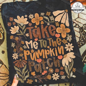 May include: Black t-shirt with the text "Take Me To The Pumpkin Patch" in brown, orange, and green. The design includes floral and leaf illustrations in shades of brown, beige, and orange, with small pumpkin graphics.