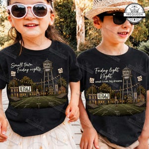 May include: Two black t-shirts featuring a graphic of a football field at night with a water tower, stadium lights, and a scoreboard displaying 4756.7. The left shirt reads Small town Friday nights, and the right shirt reads Friday light Night small town, big dreams.