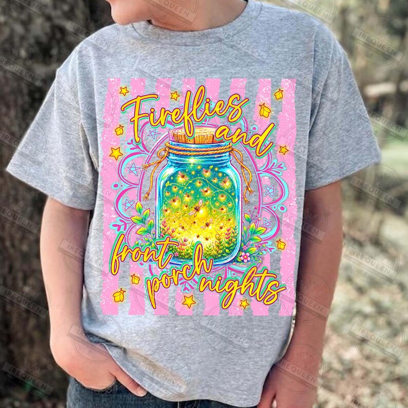 May include: A gray t-shirt featuring a colorful graphic design. The design includes a mason jar filled with fireflies, surrounded by flowers and stars, with the words "Fireflies and front porch nights" in a whimsical font.