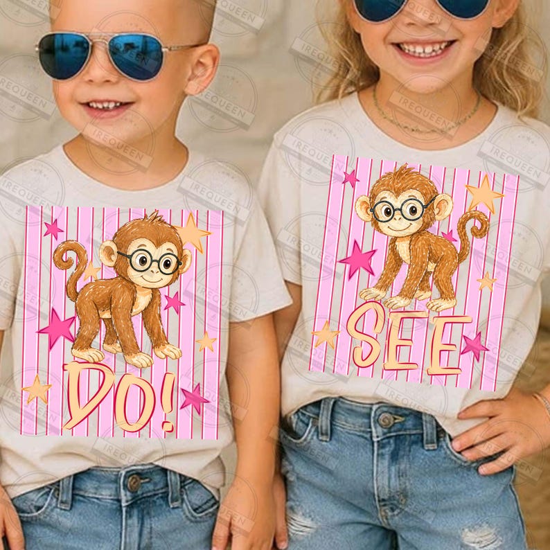 Puede incluir: Dos camisetas infantiles con un mono de dibujos animados con gafas. El mono est&aacute; sobre un fondo de rayas rosas con estrellas y la palabra "DO!" en una camiseta y "SEE" en la otra. Las camisetas son beige.