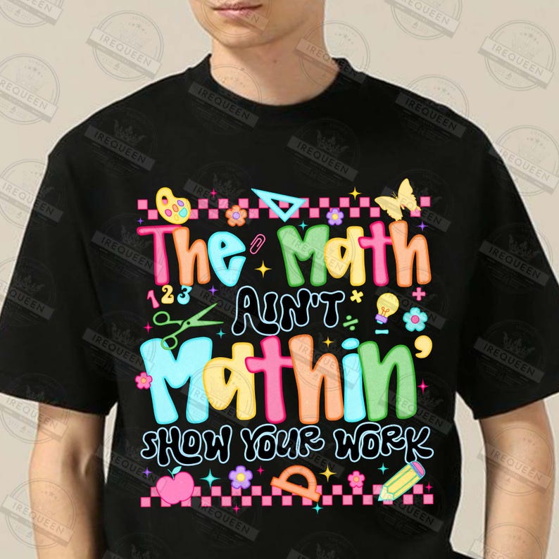 Puede incluir: Camiseta negra con la frase "The Math Ain't Mathin' Show Your Work" en letras coloridas y divertidas. El dise&ntilde;o incluye s&iacute;mbolos matem&aacute;ticos, una mariposa, tijeras y un l&aacute;piz, ideal para profesores o estudiantes.