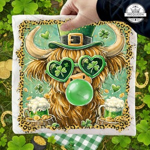 May include: A white square pillow featuring a whimsical illustration for St. Patrick's Day. The design includes a Highland cow wearing heart-shaped shamrock sunglasses, a green leprechaun hat, and blowing a bubble. The border has a gold leopard print.