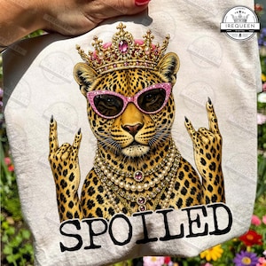 May include: A tote bag featuring a leopard illustration wearing pink sunglasses, a crown, and a pearl necklace. The leopard is making a rock-and-roll hand gesture. The word "SPOILED" is printed at the bottom.