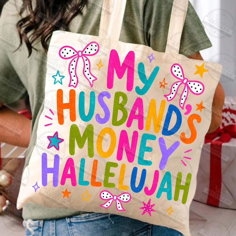 Pu&ograve; includere: Una borsa in tela color crema con il testo colorato "My Husband's Money Hallelujah" in un carattere giocoso. Il design &egrave; decorato con fiocchi a pois rosa e bianchi e varie piccole stelle nei colori arancione, rosa e blu.