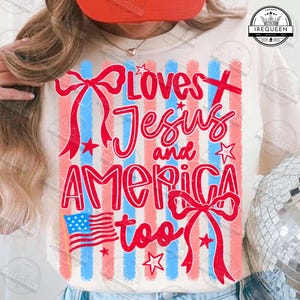 Puede incluir: Camiseta color crema con un dise&ntilde;o patri&oacute;tico. El gr&aacute;fico presenta rayas rojas y azules, estrellas y el texto "Loves Jesus and America too" en una fuente de escritura. Tambi&eacute;n se incluye una bandera estadounidense.