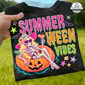 Peut inclure: T-shirt noir avec un motif coloré d'un squelette se relaxant dans une citrouille, portant un chapeau et des lunettes de soleil, tenant un cocktail. Le texte dit "Summer Ween Vibes".