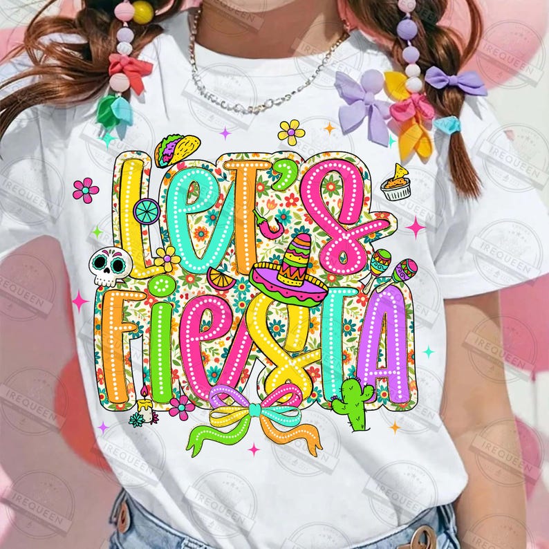 May include: White t-shirt featuring a vibrant "Let's Fiesta" design. The graphic includes a sombrero, maracas, and other festive elements. The text is outlined in bright colours, with a floral background.