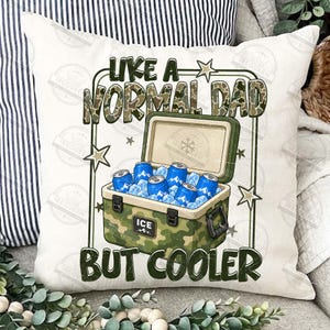 May include: A white throw pillow with a camouflage cooler graphic. The cooler is open, filled with ice and blue cans. Text reads "LIKE A NORMAL DAD BUT COOLER" in green and camouflage lettering.