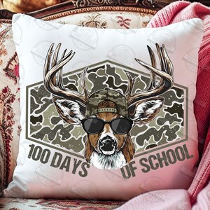 Puede incluir: Coj&iacute;n decorativo blanco con un ciervo con gafas de sol y un sombrero de camuflaje. El ciervo est&aacute; sobre un fondo de camuflaje dentro de una forma geom&eacute;trica. El texto "100 DAYS OF SCHOOL" est&aacute; impreso debajo.