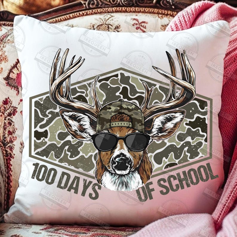 Puede incluir: Coj&iacute;n decorativo blanco con un ciervo con gafas de sol y un sombrero de camuflaje. El ciervo est&aacute; sobre un fondo de camuflaje dentro de una forma geom&eacute;trica. El texto "100 DAYS OF SCHOOL" est&aacute; impreso debajo.