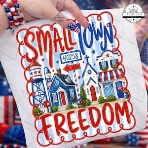 Op de afbeelding: Wit T-shirt met een patriottisch ontwerp. Het ontwerp bevat de woorden "Small Town Freedom" in rood en blauw, samen met illustraties van een watertoren, huizen en een kerk, en de postcode 40258.