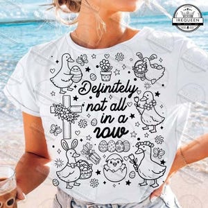 May include: White t-shirt with a black and white Easter-themed graphic. The design includes ducks, bunnies, eggs, flowers, and the text "Definitely not all in a row". The shirt is a casual, everyday wear item.