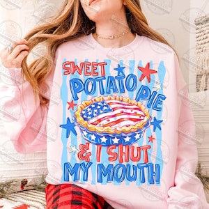 May include: Pink sweatshirt with a graphic of a sweet potato pie decorated with the American flag. The text reads "SWEET POTATO PIE & I SHUT MY MOUTH" in blue and red. The design includes stars and stripes.