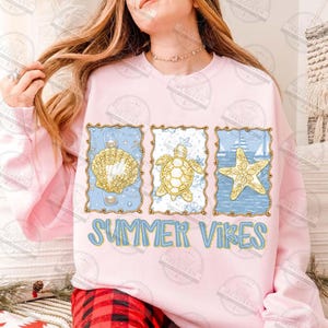 May include: A light pink sweatshirt with a blue and gold design featuring a seashell, turtle, and starfish. The words "SUMMER VIBES" are printed in blue below the images.