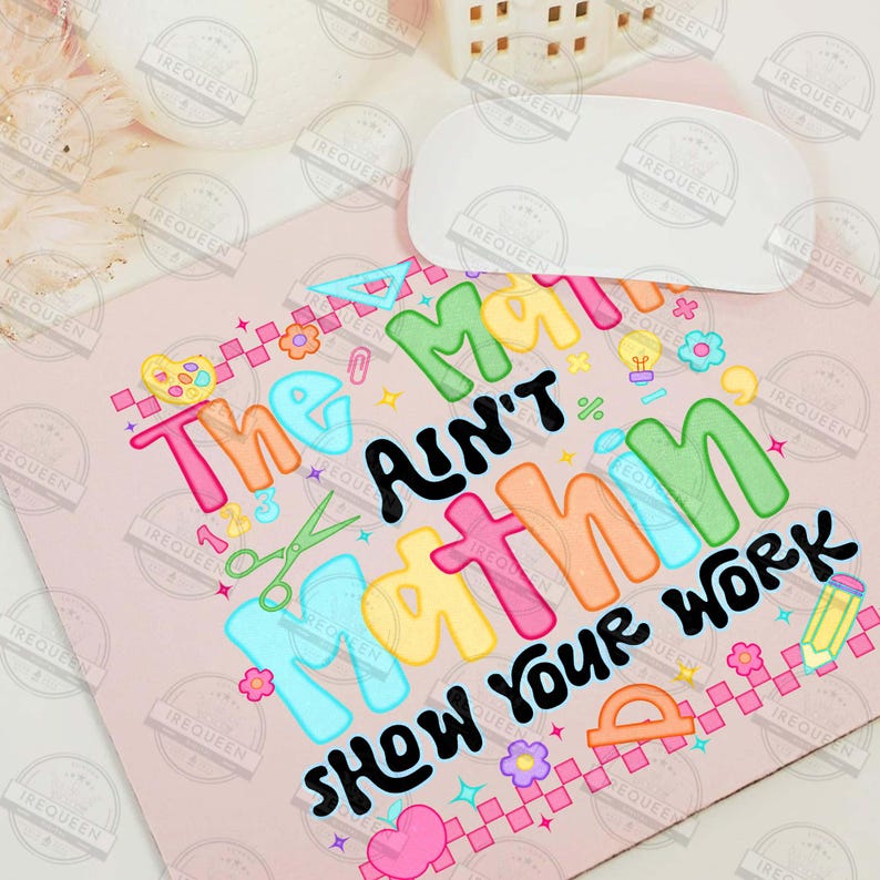 Puede incluir: Una alfombrilla de rat&oacute;n rosa con el texto "The math ain't mathin' show your work" en letras coloridas. El dise&ntilde;o incluye gr&aacute;ficos escolares como tijeras, un transportador y un l&aacute;piz.