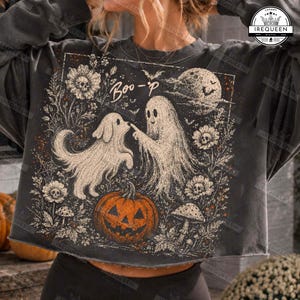 Puede incluir: Una sudadera corta de color gris carbón con un estampado gráfico de un fantasma y un perro fantasma tocándose las narices. El diseño incluye una gran calabaza naranja, flores con centros de calavera, setas y una luna llena con el texto Boo-p.