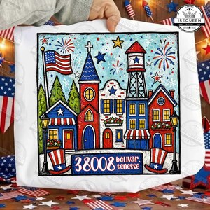 May include: A white tote bag featuring a colorful illustration of a patriotic town scene. The artwork includes an American flag, fireworks, and buildings in red, white, and blue. The text "38008 bolivar tenesse" is also visible.