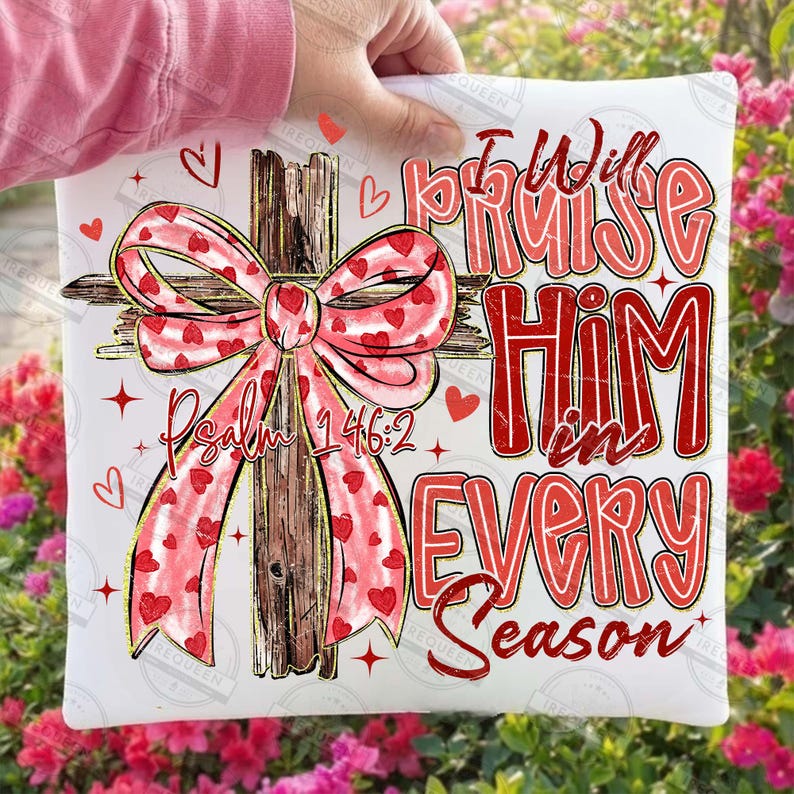 May include: White square pillow with a cross design. The cross is made of wood and has a pink bow with red hearts. The text "I Will Praise Him in Every Season" is in red. The text "Psalm 146:2" is also visible.