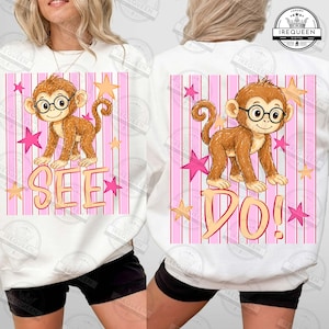 Puede incluir: Sudadera blanca con un mono de dibujos animados con gafas y la palabra "SEE" impresa debajo. El dise&ntilde;o incluye rayas rosas y blancas, estrellas rosas y estrellas amarillas.