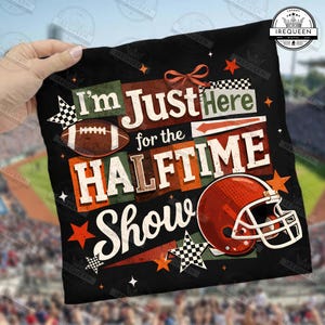 May include: Black graphic tee with the text "I'm Just Here for the Halftime Show." Features a football, a football helmet, and star accents in orange, white, and green.