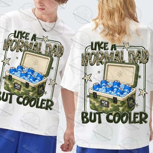 May include: White t-shirts with a graphic design. The design features the text "LIKE A NORMAL DAD BUT COOLER" above a camouflage cooler filled with ice and blue cans. The cooler has the word "ICE" on it.