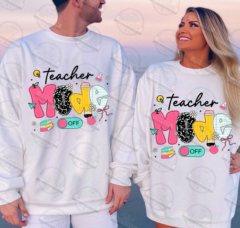 May include: White long-sleeved shirts with a graphic print of the words "Teacher Mode" in pink, yellow, and black with a light blue on/off switch. The graphic includes a variety of school-themed icons such as a lightbulb, apple, pencil, and books.
