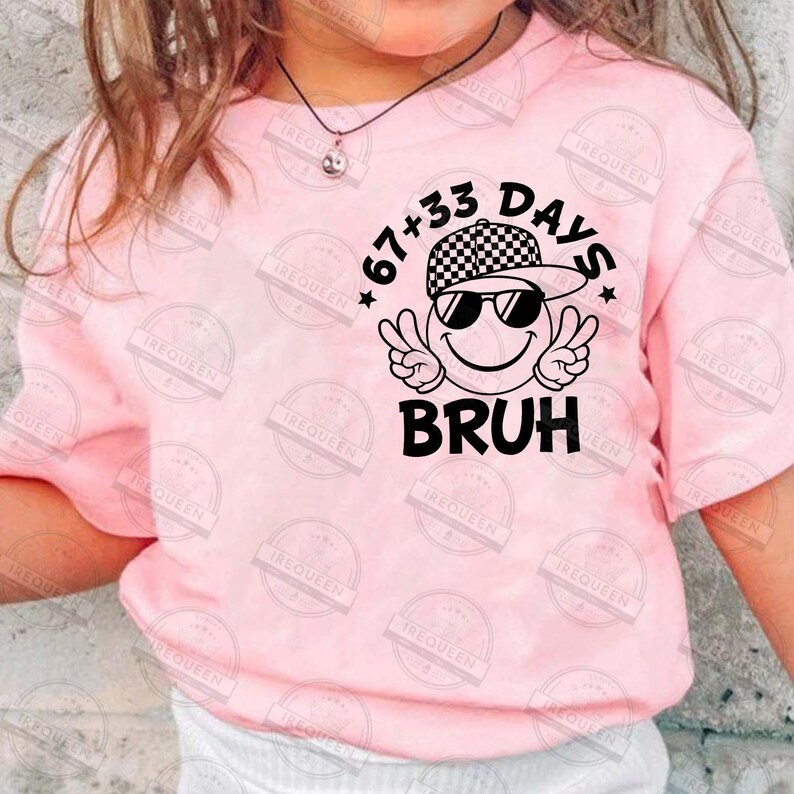 Pu&ograve; includere: Una maglietta rosa chiaro con un design grafico. Il design include una faccina sorridente con occhiali da sole e un cappello a scacchi, con la scritta "67+33 DAYS BRUH". La maglietta &egrave; a maniche corte.