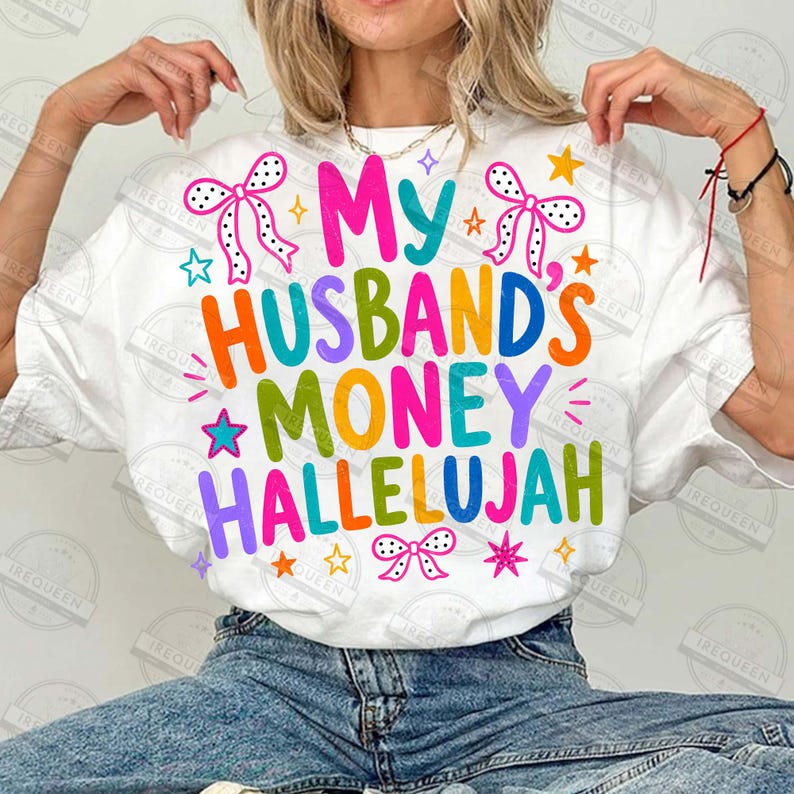Pu&ograve; includere: Una t-shirt bianca a maniche corte con il testo colorato My Husband's Money Hallelujah in varie tonalit&agrave; vivaci. Il design include illustrazioni grafiche di fiocchi a pois e piccole stelle che circondano la scritta stampata.