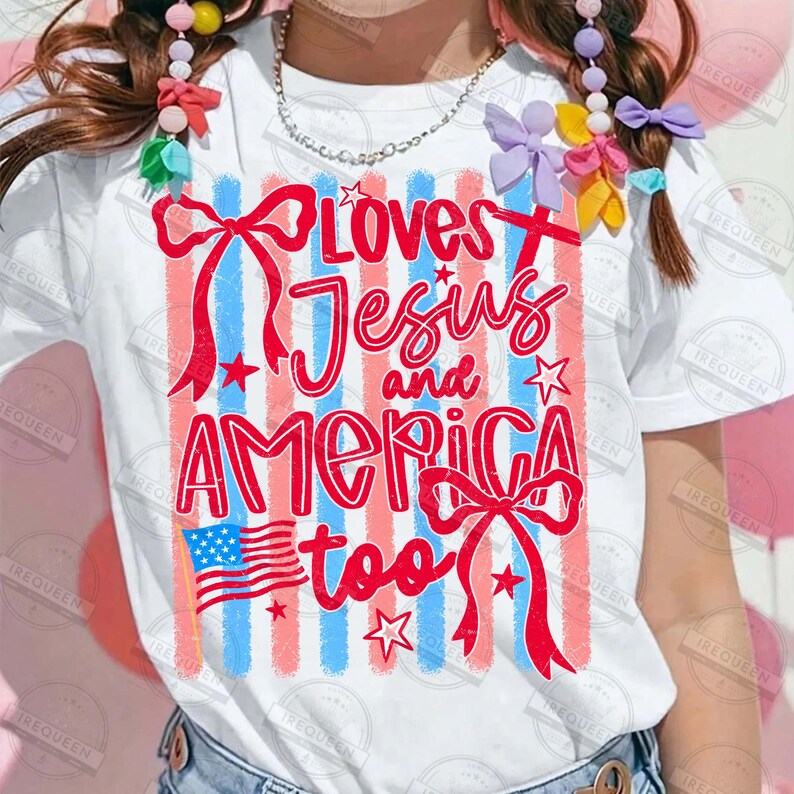 Puede incluir: Camiseta blanca con un dise&ntilde;o patri&oacute;tico. La camiseta presenta rayas verticales rojas y azules, una peque&ntilde;a bandera estadounidense y el texto "Loves Jesus and America too" en escritura roja. Los lazos y estrellas rojas completan el dise&ntilde;o.