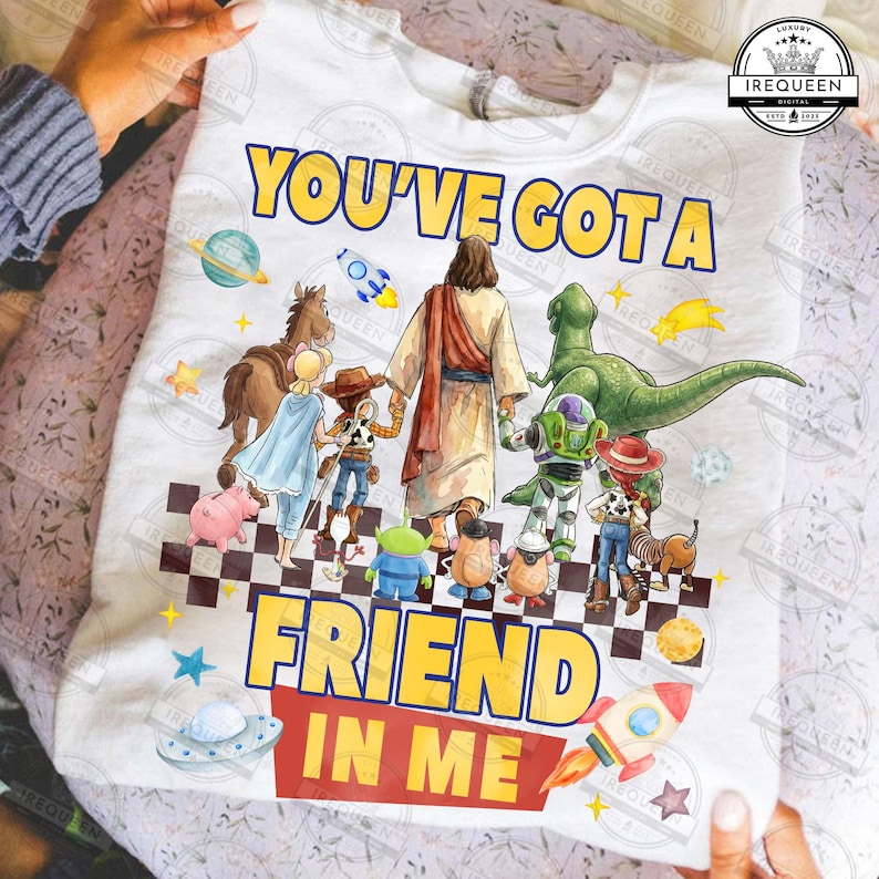 May include: White t-shirt with the text "YOU'VE GOT A FRIEND IN ME" in yellow and red. The design features cartoon characters including Jesus, a dinosaur, and characters from Toy Story. A rocket and a UFO are also included in the design.